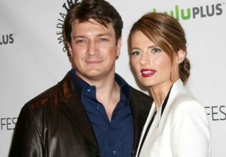 Actor Nathan Fillion in a black jacket poses a picture with Stana Katic.